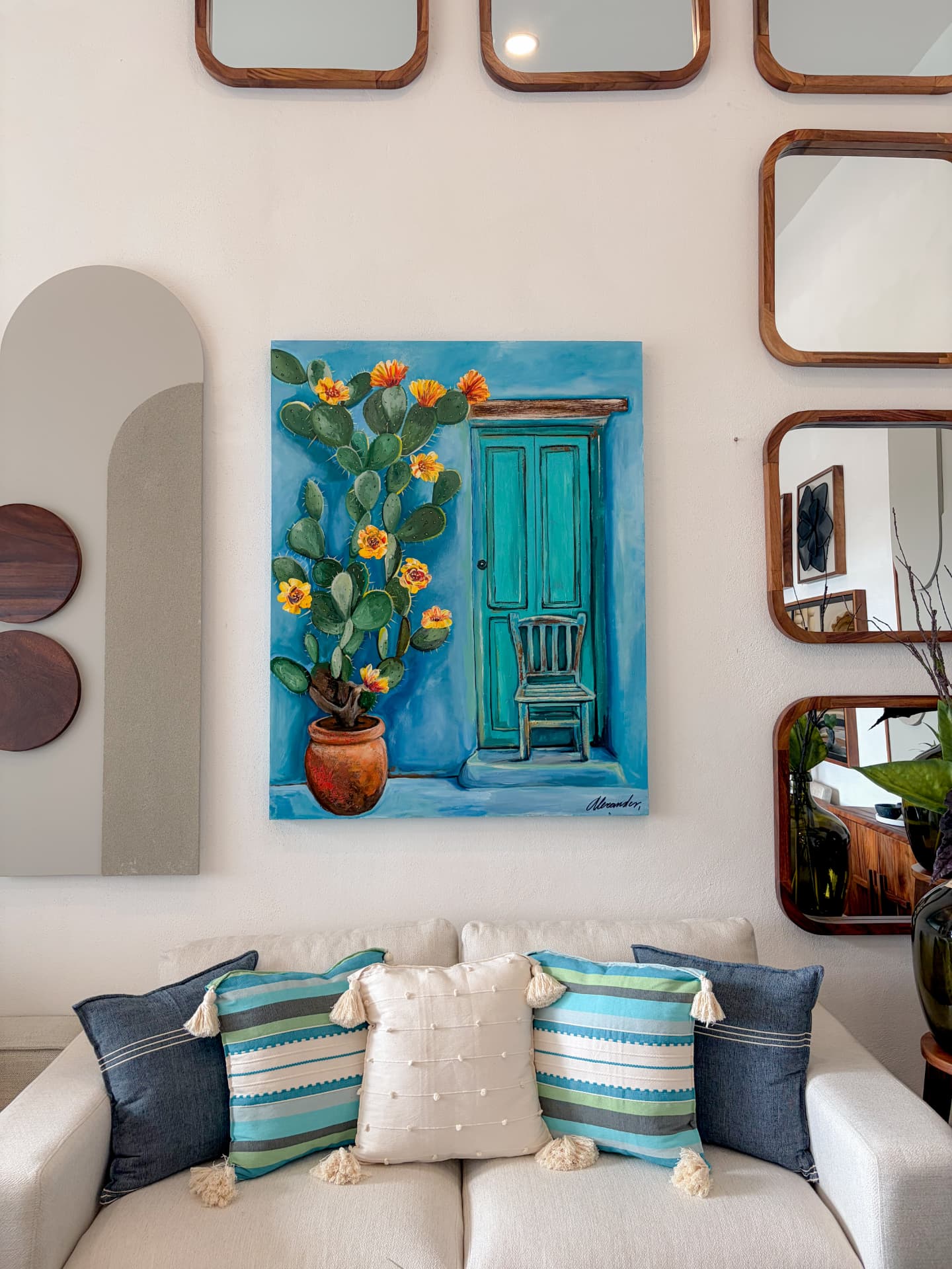Obra de cactus en flor sobre sala con espejos de madera en el showroom Mezquite, Los Cabos