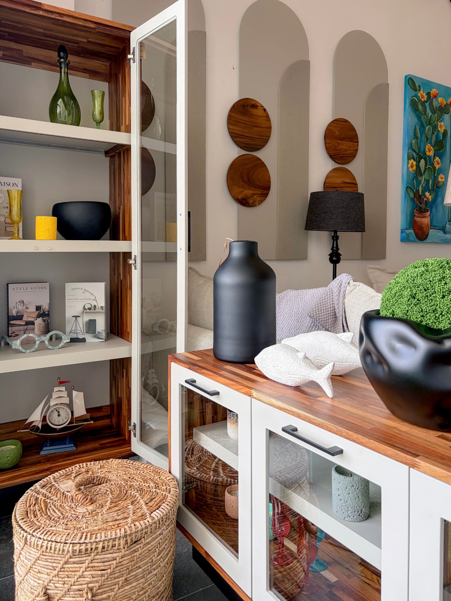 Vitrina de madera con libros y objetos junto a decoración de madera en el showroom Mezquite