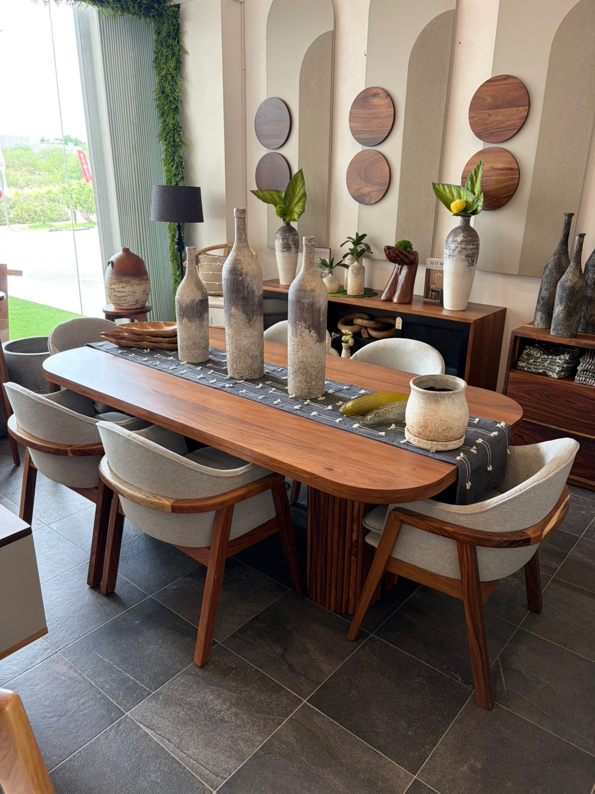 Comedor de parota con sillas tapizadas y objetos de decoración en el showroom Mezquite, Los Cabos