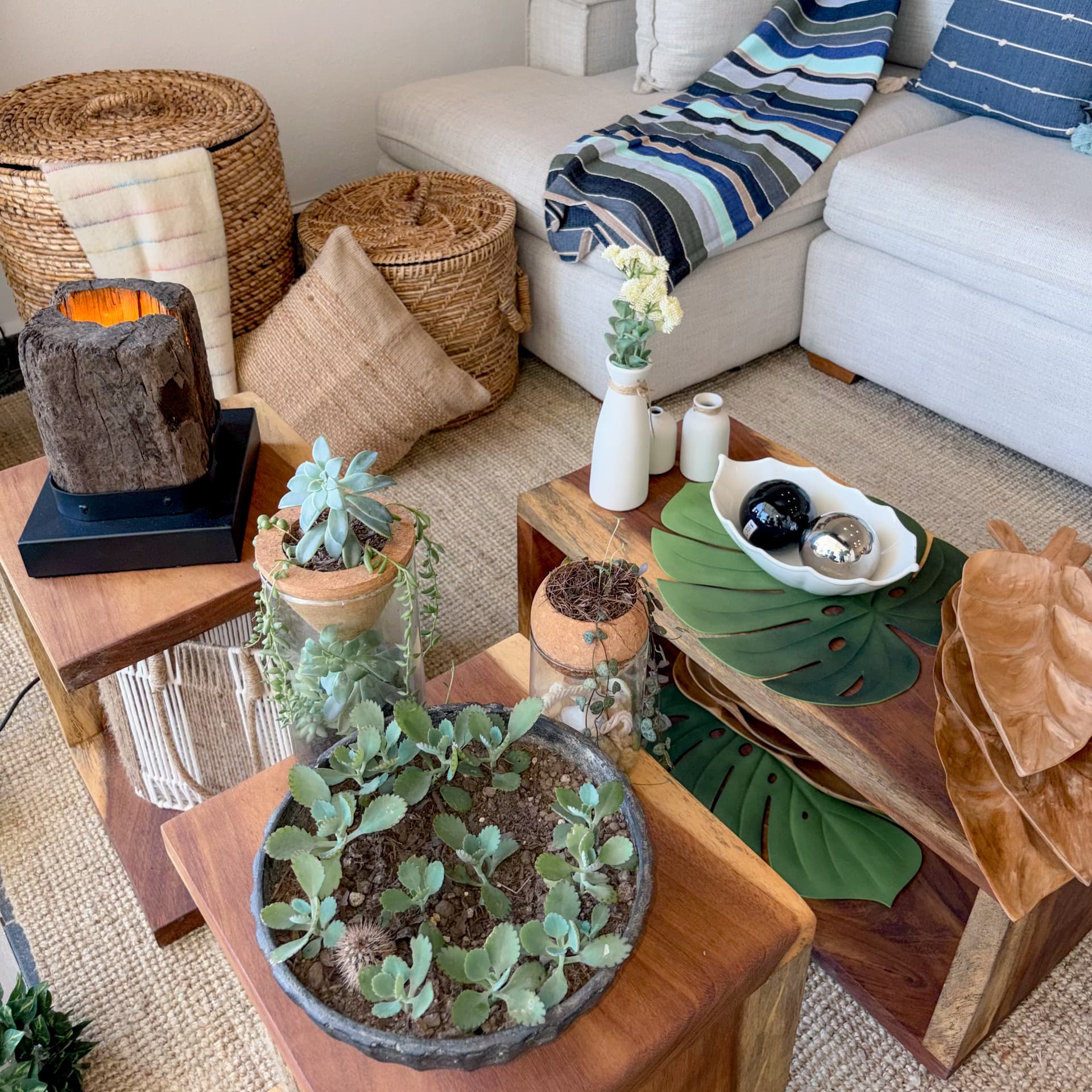 Mesas de centro de madera maciza con objetos, plantas y textiles en sala Mezquite